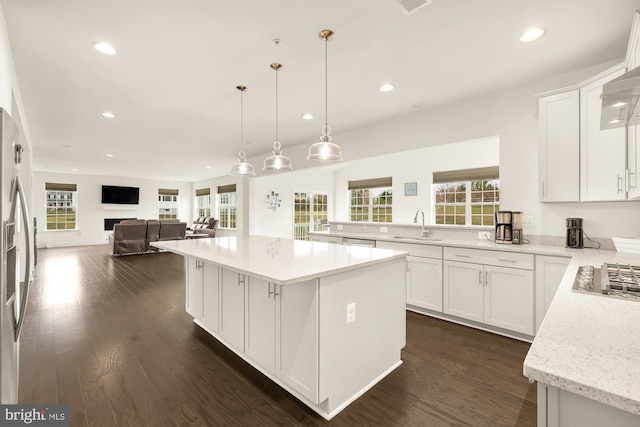 kitchen with a sink, white cabinetry, open floor plan, a center island, and dark wood-style floors