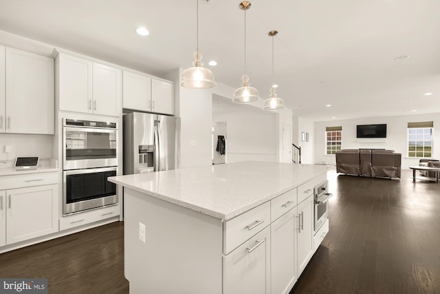 kitchen featuring white cabinetry, stainless steel appliances, dark wood finished floors, and open floor plan