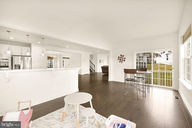 dining space featuring dark wood-type flooring, recessed lighting, high vaulted ceiling, and stairs