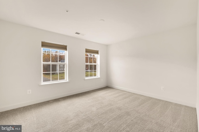 spare room with carpet floors, baseboards, and visible vents