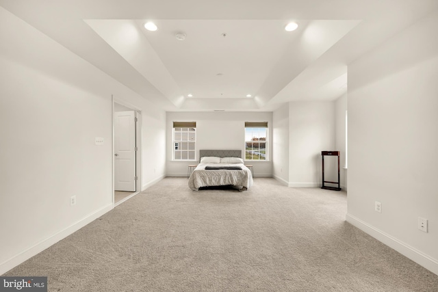 unfurnished bedroom featuring carpet floors, baseboards, a tray ceiling, and recessed lighting