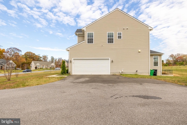 view of side of property with a garage, driveway, and a lawn