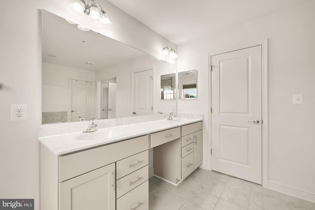 full bath with double vanity, a sink, and baseboards