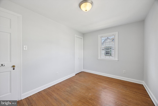 spare room featuring baseboards and hardwood / wood-style flooring