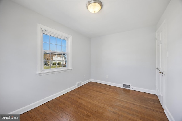 spare room featuring visible vents, baseboards, and wood finished floors