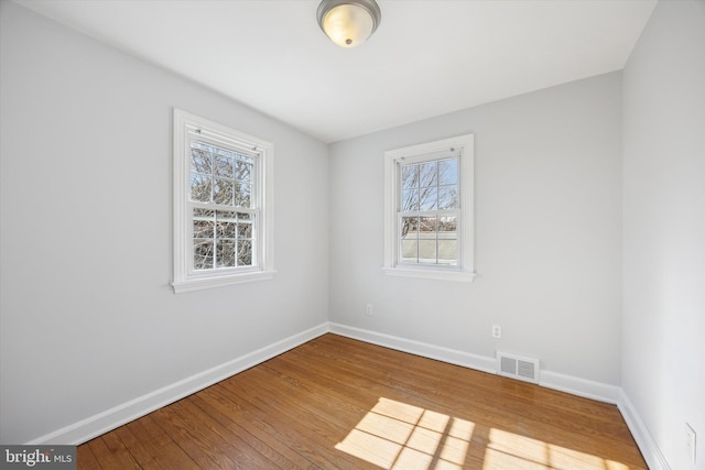 spare room with visible vents, baseboards, and hardwood / wood-style flooring