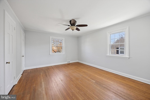 unfurnished bedroom featuring baseboards, multiple windows, wood-type flooring, and crown molding