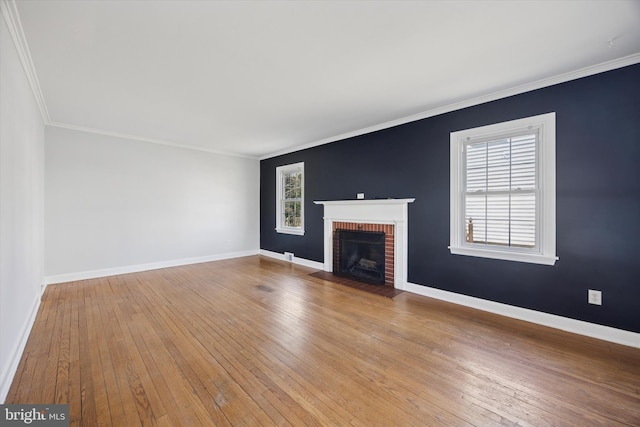 unfurnished living room featuring hardwood / wood-style floors, crown molding, a brick fireplace, and baseboards