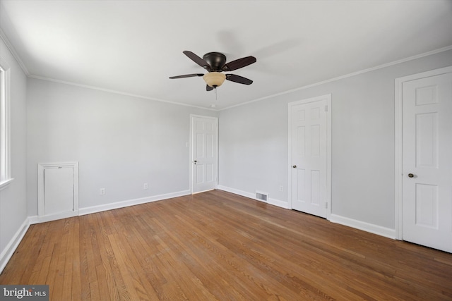 unfurnished bedroom featuring visible vents, ornamental molding, a ceiling fan, wood-type flooring, and baseboards