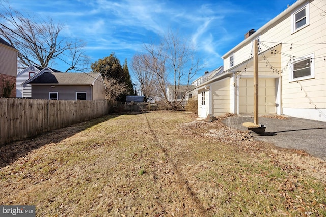 view of yard with an attached garage and fence