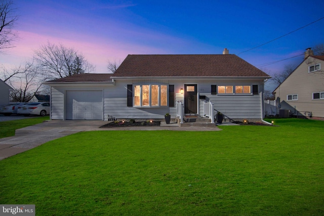 ranch-style house featuring central AC unit, an attached garage, a lawn, and driveway