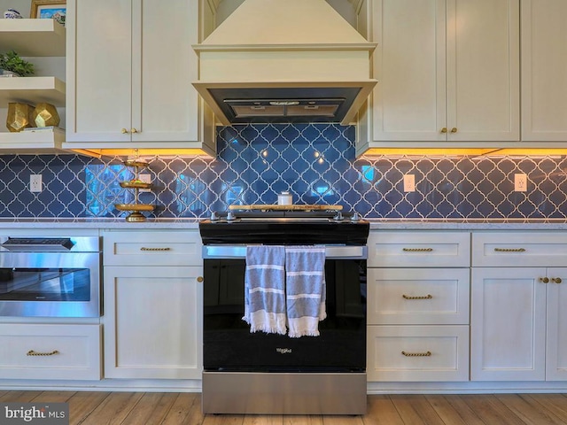 kitchen featuring stainless steel appliances, premium range hood, light countertops, decorative backsplash, and open shelves