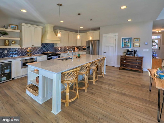 kitchen with a sink, open shelves, appliances with stainless steel finishes, and custom exhaust hood