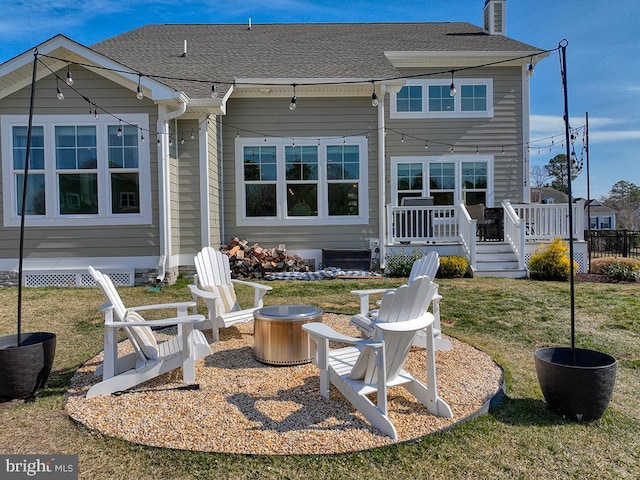 back of house with roof with shingles, a chimney, a fire pit, and a wooden deck