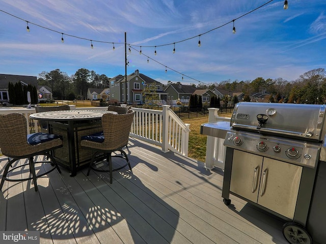 wooden terrace featuring a residential view, outdoor dining area, a grill, and fence