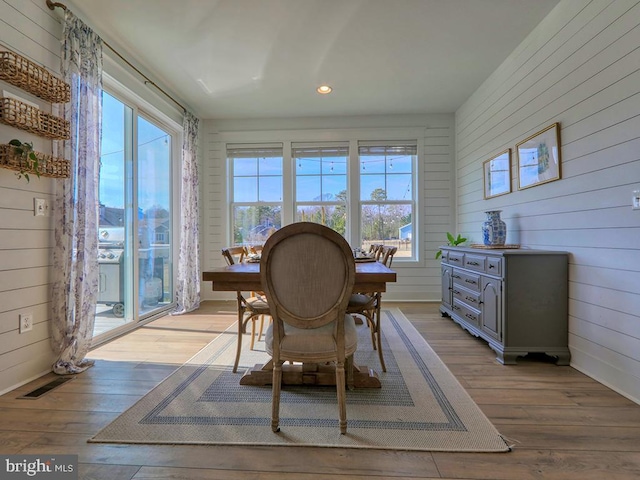 dining space featuring wooden walls, wood finished floors, and recessed lighting