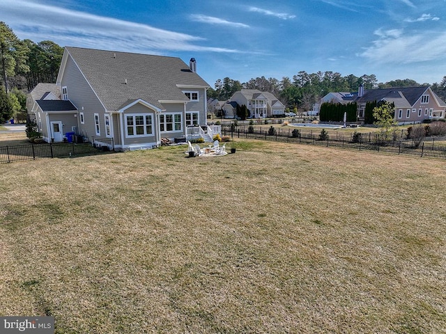 rear view of house with a fenced backyard and a yard