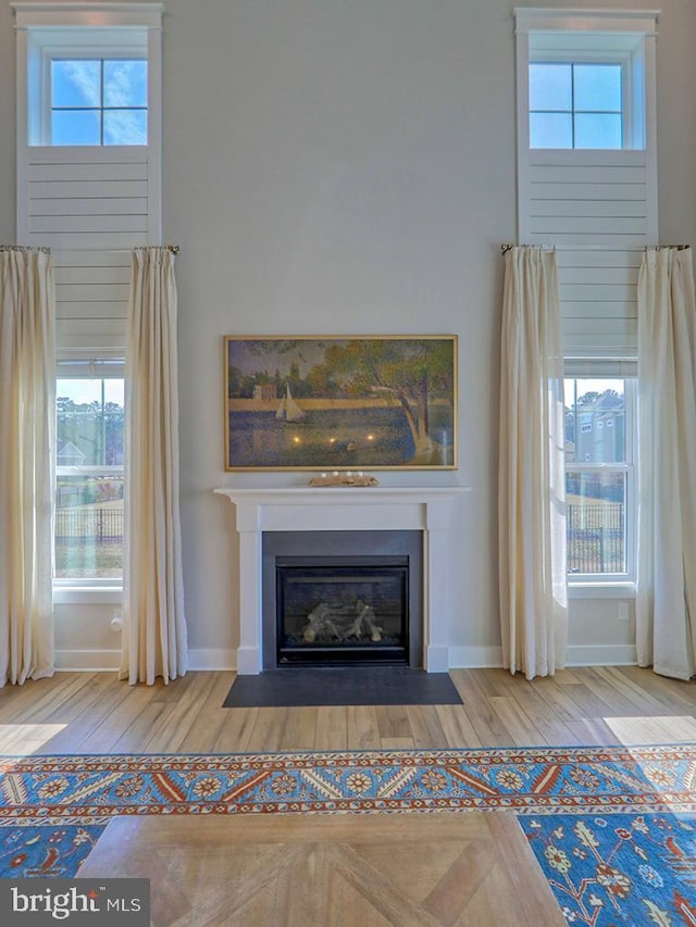 room details featuring a fireplace with flush hearth, baseboards, and wood finished floors