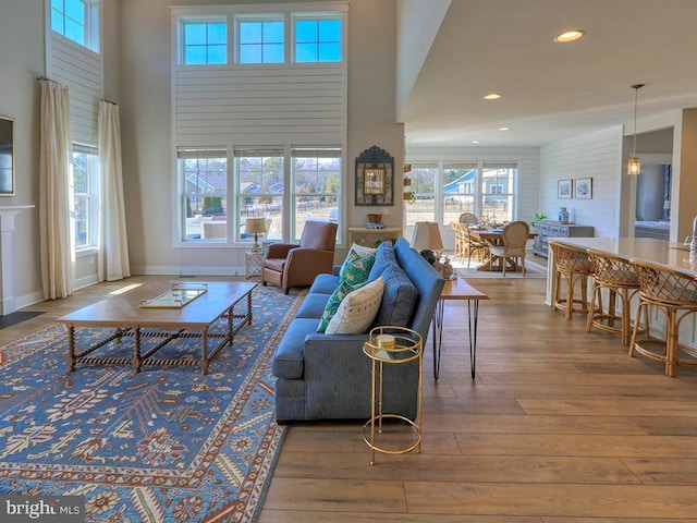 living room with baseboards, wood finished floors, a towering ceiling, and recessed lighting