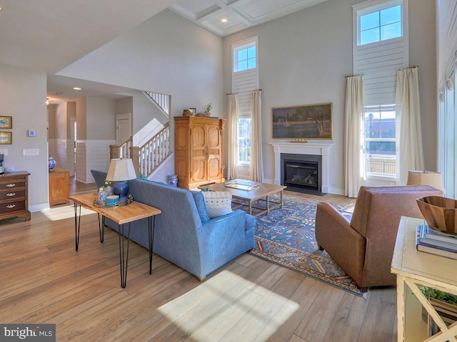 living room featuring a towering ceiling, a healthy amount of sunlight, stairs, and wood finished floors