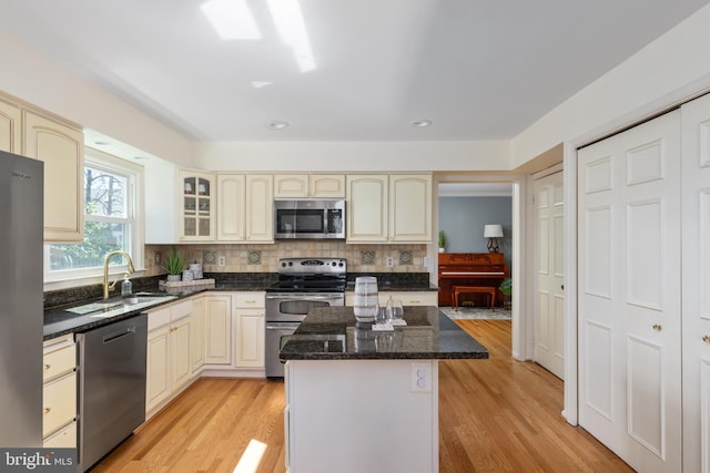 kitchen with cream cabinetry, a sink, a kitchen island, stainless steel appliances, and decorative backsplash