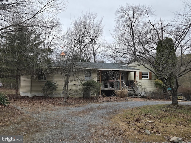 view of front facade with dirt driveway, a porch, and a chimney