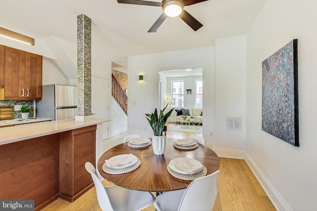 dining room featuring visible vents, baseboards, ceiling fan, light wood-style flooring, and stairway