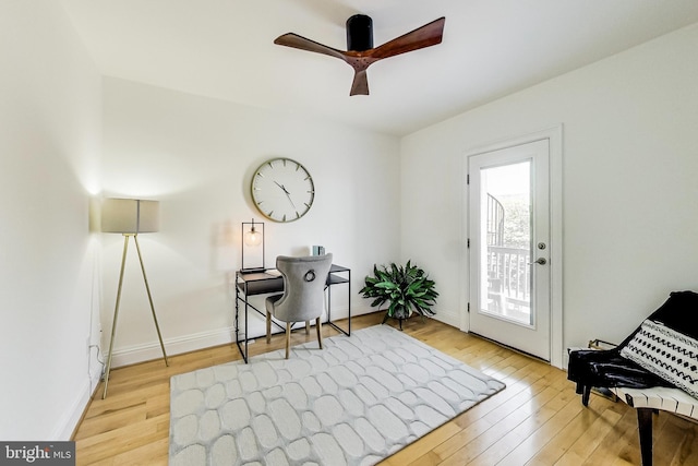 office area featuring light wood-type flooring, a ceiling fan, and baseboards