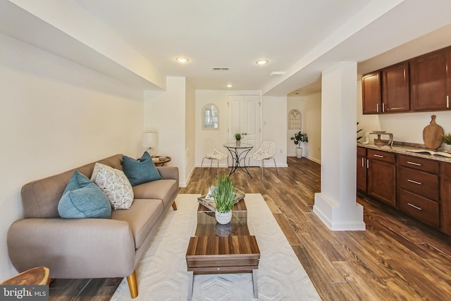 living room with recessed lighting, visible vents, baseboards, dark wood finished floors, and ornate columns