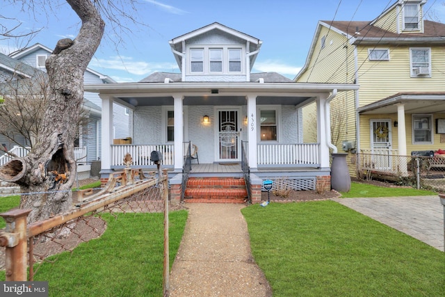 view of front of property featuring covered porch, fence, and a front yard