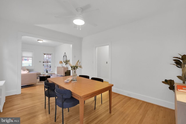 dining room featuring baseboards, ceiling fan, and light wood finished floors