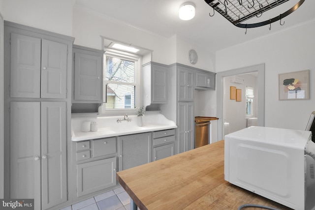 kitchen with light tile patterned floors, ornamental molding, gray cabinets, and wooden counters