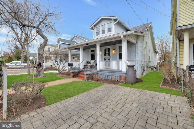 bungalow-style house with covered porch, fence, and a front yard