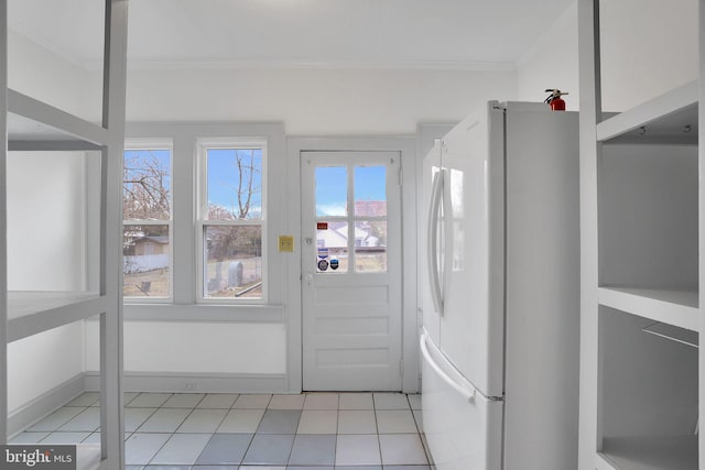 doorway featuring crown molding, baseboards, and light tile patterned floors