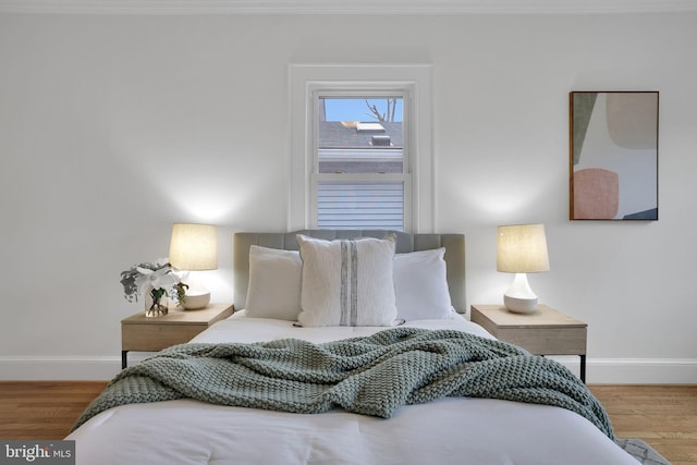 bedroom featuring ornamental molding, baseboards, and wood finished floors