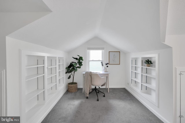 home office with lofted ceiling, built in shelves, carpet, and baseboards