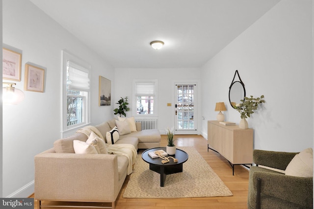 living area featuring radiator heating unit, light wood-style flooring, and baseboards