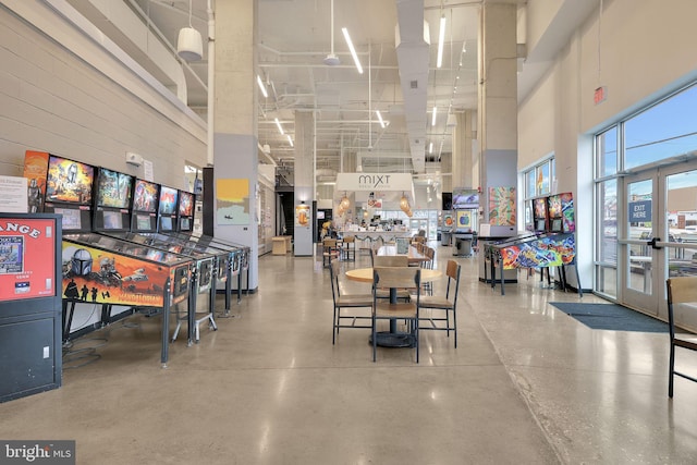 dining area featuring finished concrete flooring and a towering ceiling