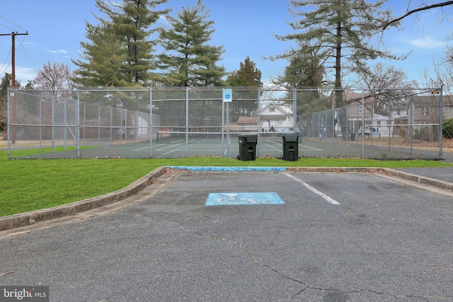 uncovered parking lot with a tennis court and fence