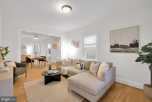 living room with a ceiling fan, baseboards, and light wood finished floors