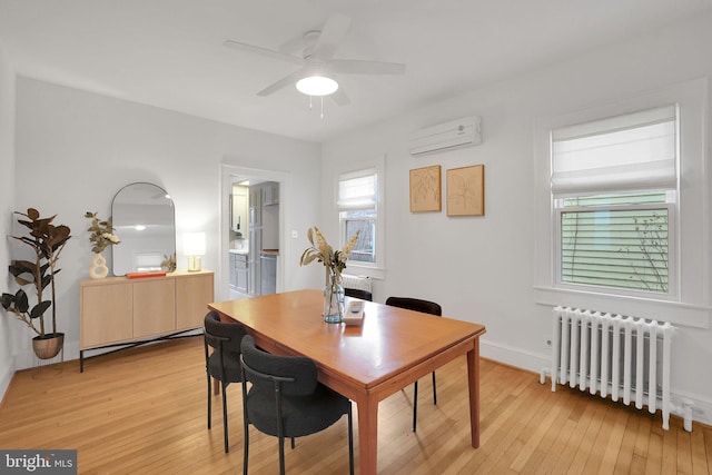 dining room featuring a wall unit AC, light wood-type flooring, radiator heating unit, and baseboard heating