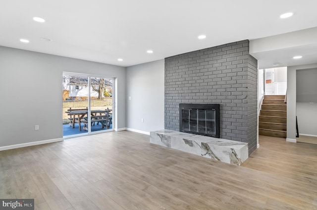 unfurnished living room with a brick fireplace, wood finished floors, and recessed lighting