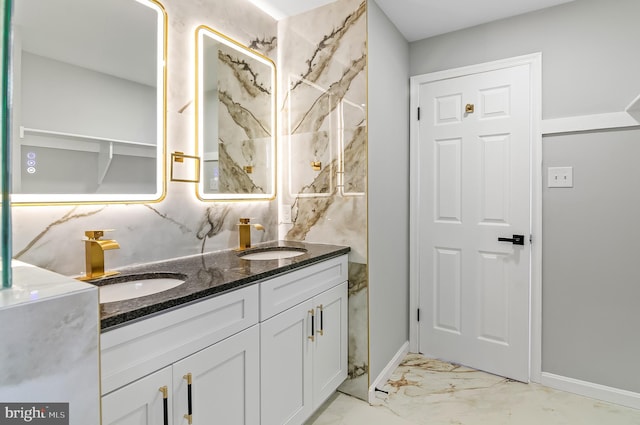 full bathroom with double vanity, marble finish floor, baseboards, and a sink