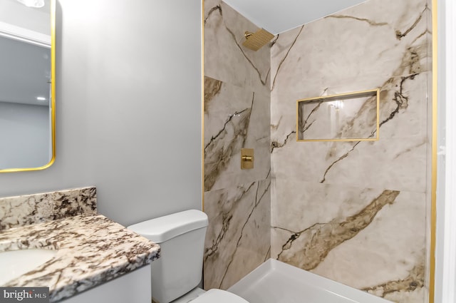 full bathroom featuring toilet, a marble finish shower, and vanity