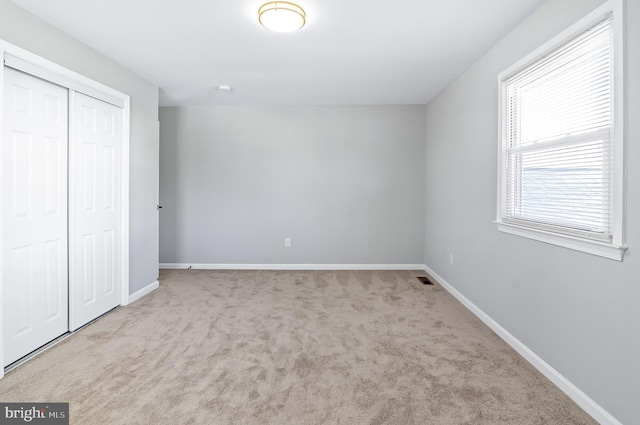 unfurnished bedroom featuring a closet, carpet, and baseboards