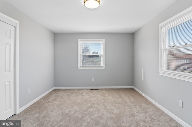 spare room with carpet flooring, visible vents, and baseboards