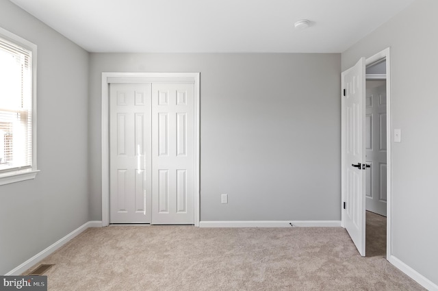 unfurnished bedroom with carpet, a closet, visible vents, and baseboards