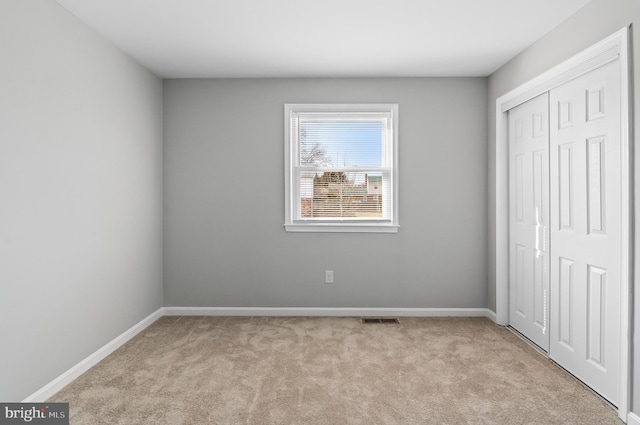 unfurnished bedroom featuring a closet, carpet, visible vents, and baseboards