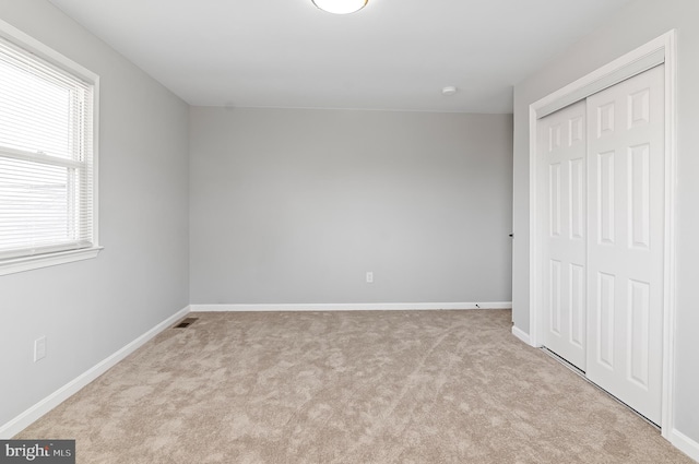 unfurnished bedroom featuring carpet floors, a closet, visible vents, and baseboards