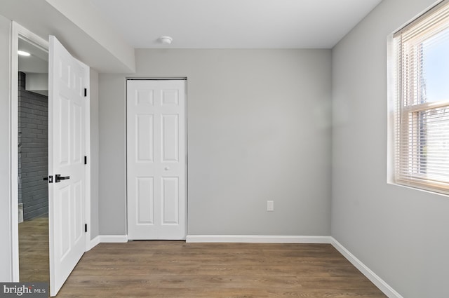 unfurnished bedroom featuring a closet, wood finished floors, and baseboards